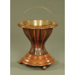 A Dutch staved walnut tea bucket, circular, with brass handle and raised on three ball feet.