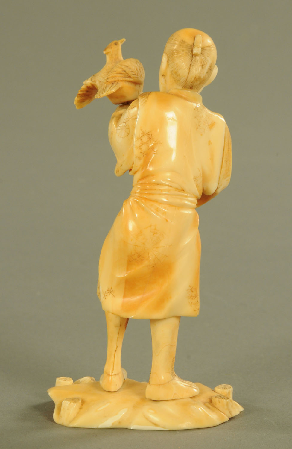 A late 19th/early 20th century Japanese carved ivory figure, male with bird, signed to base. - Image 2 of 3