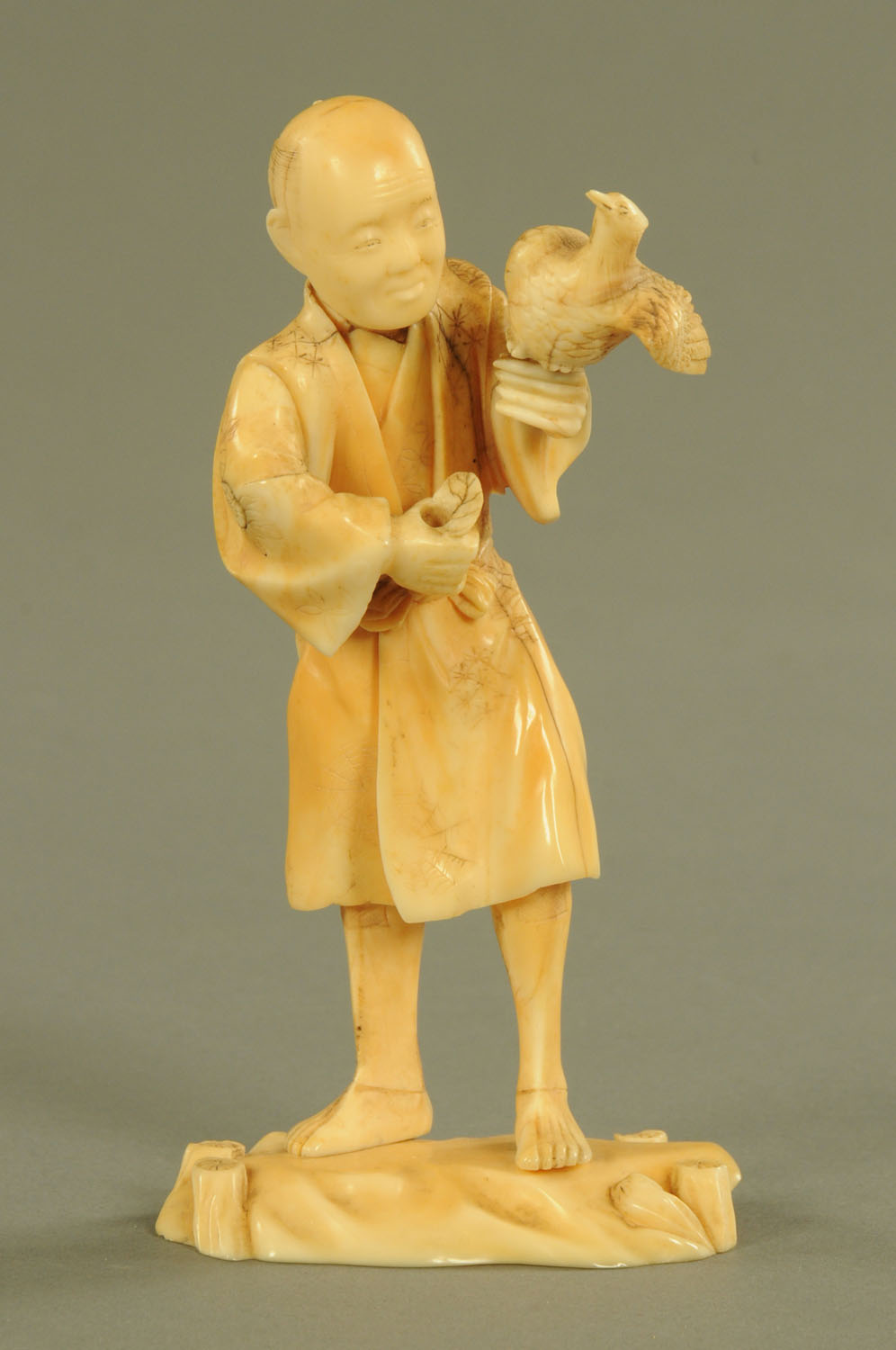 A late 19th/early 20th century Japanese carved ivory figure, male with bird, signed to base.