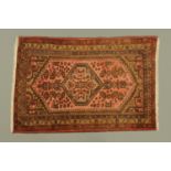 An Eastern fringed rug, principal colours pink, blue and brown, with multiple line border.