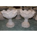 Two circular decorative garden planters on pedestals