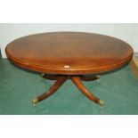 Large mahogany oval coffee table with central column and raised on 4 reeded legs with hairy paw