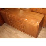 An Ercol light elm sideboard fitted with three central drawers flanked by cupboards,