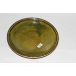 A green glazed stoneware studio pottery circular bowl with black trailed rim,