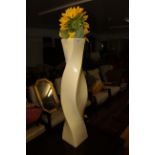 A large twisted square section resin vase containing artificial sunflowers, height 70 cm.