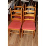 A set of four modern pine ladder back dining chairs, the seats upholstered in red material,