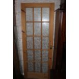 A modern pine internal door, having 15 textured glass panels and brass furniture, 196 x 76 cm.