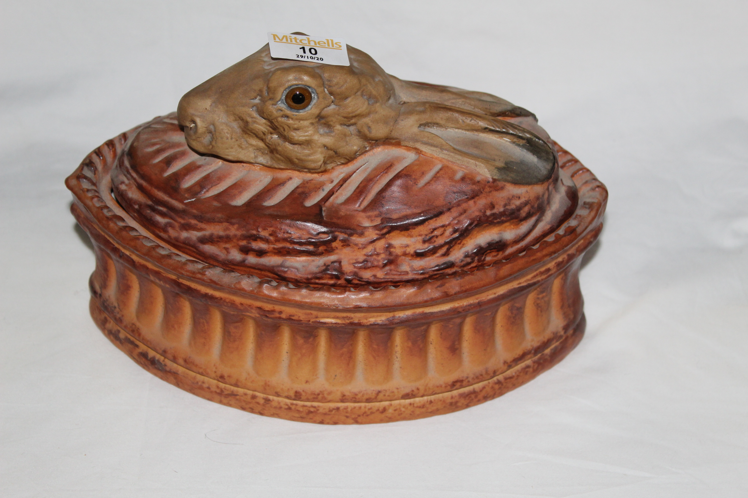 A 19th century pottery oval hare pie dish, the lid model with hares heads with glass eyes.