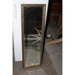 A gilt framed rectangular mirror with bevelled plates, 124 x 40 cm.