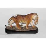 An Academy resin figure of a tiger and cub on wooden effect plinth, 23 cm high.
