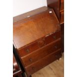 A 1940's oak bureau with fall front over three long drawers,