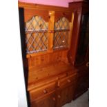 A pine dresser, the upper part enclosed by a pair of leaded glazed doors,