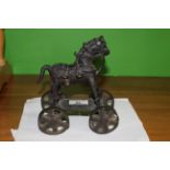 An unusual Indonesian ground painted bronze model of a hobby horse on wheels, 18 cm high.