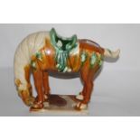 A Tang style pottery horse, decorated in traditional colours of tan, green and cream, 24 cm high.
