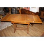 An early 20th century light oak drawer leaf dining table,