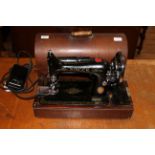 A vintage electric singer sewing machine housed in a traditional walnut domed case with carry
