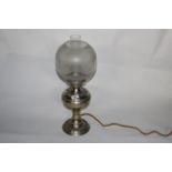 An embossed white metal table oil lamp with chimney and etched glass shade,
