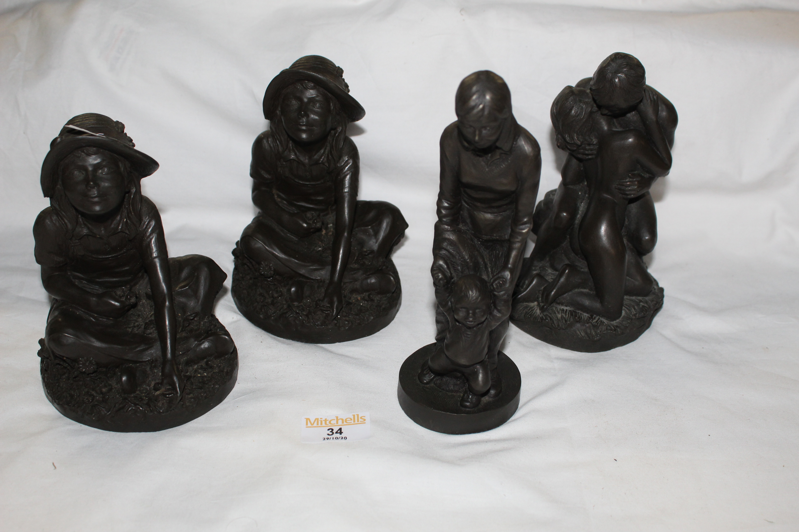 Four Heredities bronzed resin figures - two of seated girl wearing wide rim hats,