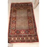 A small machine made rug of Persian design with central rectangular panel enclosed by foliate