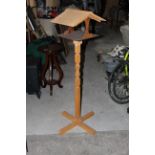 A modern stained pine pedestal bird feeder with traditional form with geometrically carved stem and