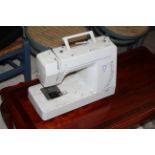 A singer silver model 2000 electric sewing machine, with white plastic cover and vinyl outer cover.