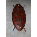 An African painted wood souvenir shield, together with two spears. The shield 80 cm x 35 cm.