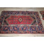A Persian Shirvan rug having a central stylised gul medallion against a brick red field and