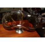 A large amber tinted asymmetric fruit bowl with chromium plated conical stand, +/- 18 cm x 34 cm.