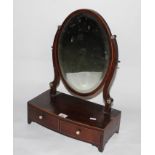 A George III mahogany toilet mirror with central oval bevelled plate between shaped uprights,