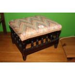 An early 20th century footstool the padded seat with geometric polychrome material above a spindled