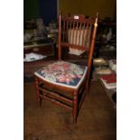 A late Victorian bedroom chair with shaped top rail above slender tapering spindles and a shaped