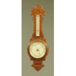 An early 20th century carved oak Aneroid barometer, with ceramic dial and scale. 81 cm.