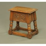 An oak box stool with lift up top and carved frieze raised on turned legs with low stretchers.