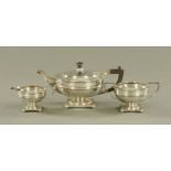 A three piece silver tea service, each piece raised on a square foot with scroll feet,