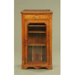 A Victorian walnut music cabinet, with canted angles, glazed door and shelves with plinth base.
