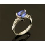 An 18 ct white gold ring, set with a trilliant cut tanzanite and with diamonds to shoulders,