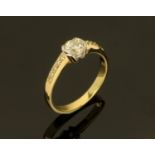 An 18 ct gold two tone ring, set with a diamond to centre and with diamond set shoulders, size M/N.