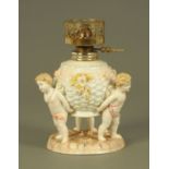 A Sitzendorf oil lamp base, three cherubs holding the reservoir. Height 21 cm.