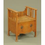 An Arts & Crafts oak commode, with stylised carving. Width 54.5 cm.