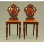 A pair of 19th century mahogany hall chairs, with carved backs,