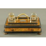 A walnut and ebonised desk inkwell stand, with centre carrying handle with two glass inkwells,
