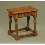 An oak joint stool, with carved frieze and fluted legs and with low stretchers. Width 50 cm.
