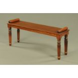 A William IV style mahogany window seat, with bolster ends and raised on turned reeded legs.