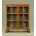 An oak glazed bookcase, circa 1900 with glazed panelled doors and raised on bracket feet.