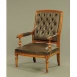 A late Victorian walnut armchair upholstered in brown leather,