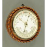 A late Victorian carved walnut circular cased aneroid barometer with thermometer. Diameter 34 cm.