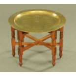 An Eastern brass topped occasional table, with folding pine base with six legs.
