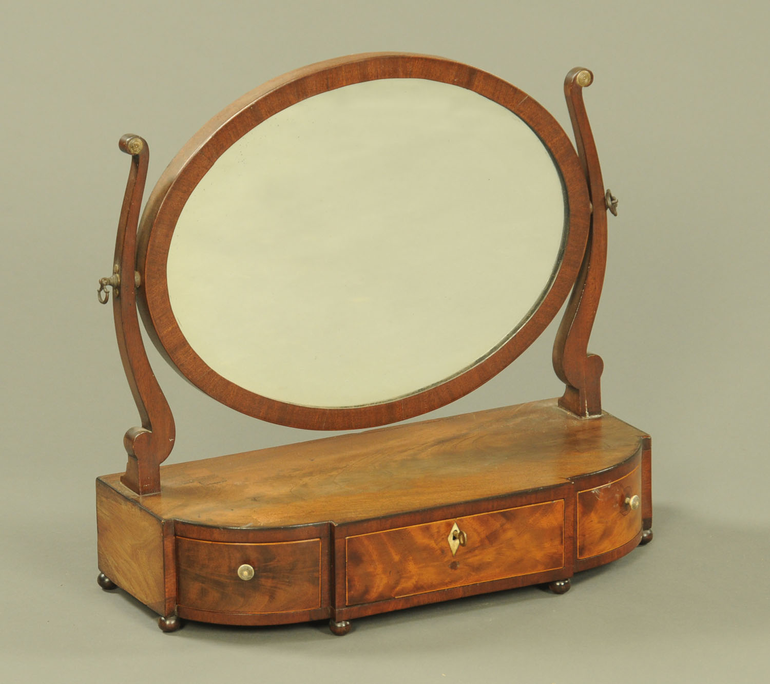 A mahogany framed oval toilet mirror, fitted with three drawers to the base.