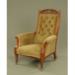 A late 19th century Arts and Crafts carved walnut armchair, with deep buttoned back,
