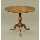 A George III oak circular tripod table, with snap action,